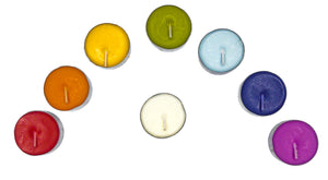 An overhead view of a box of scented chakra healing candles. Shows eight candles, colored, red, orange, yellow, green, light blue, indigo, violet and white.