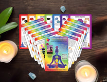Load image into Gallery viewer, full deck of chakra healing cards spread out on a wooden table with candles, crystals and a plant.